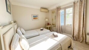 A double bed with a headboard, a bedside table with a lamp, a small table with a mirror, and a window with curtains. - Cannes: Duplex 5 bedrooms Apartment with terraces 1 minute from the Palais (Cannes)