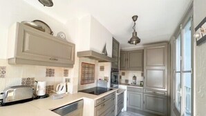 A kitchen with a central island, built-in appliances, and a window providing natural light. - Cannes: Duplex 5 bedrooms Apartment with terraces 1 minute from the Palais (Cannes)