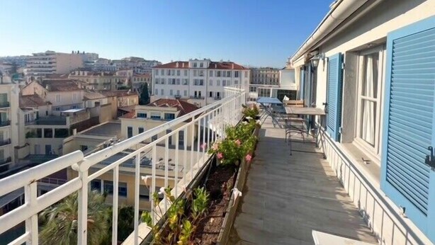 A balcony with a view of surrounding buildings, a railing, and some potted plants. - Cannes: Duplex 5 bedrooms Apartment with terraces 1 minute from the Palais (Cannes)