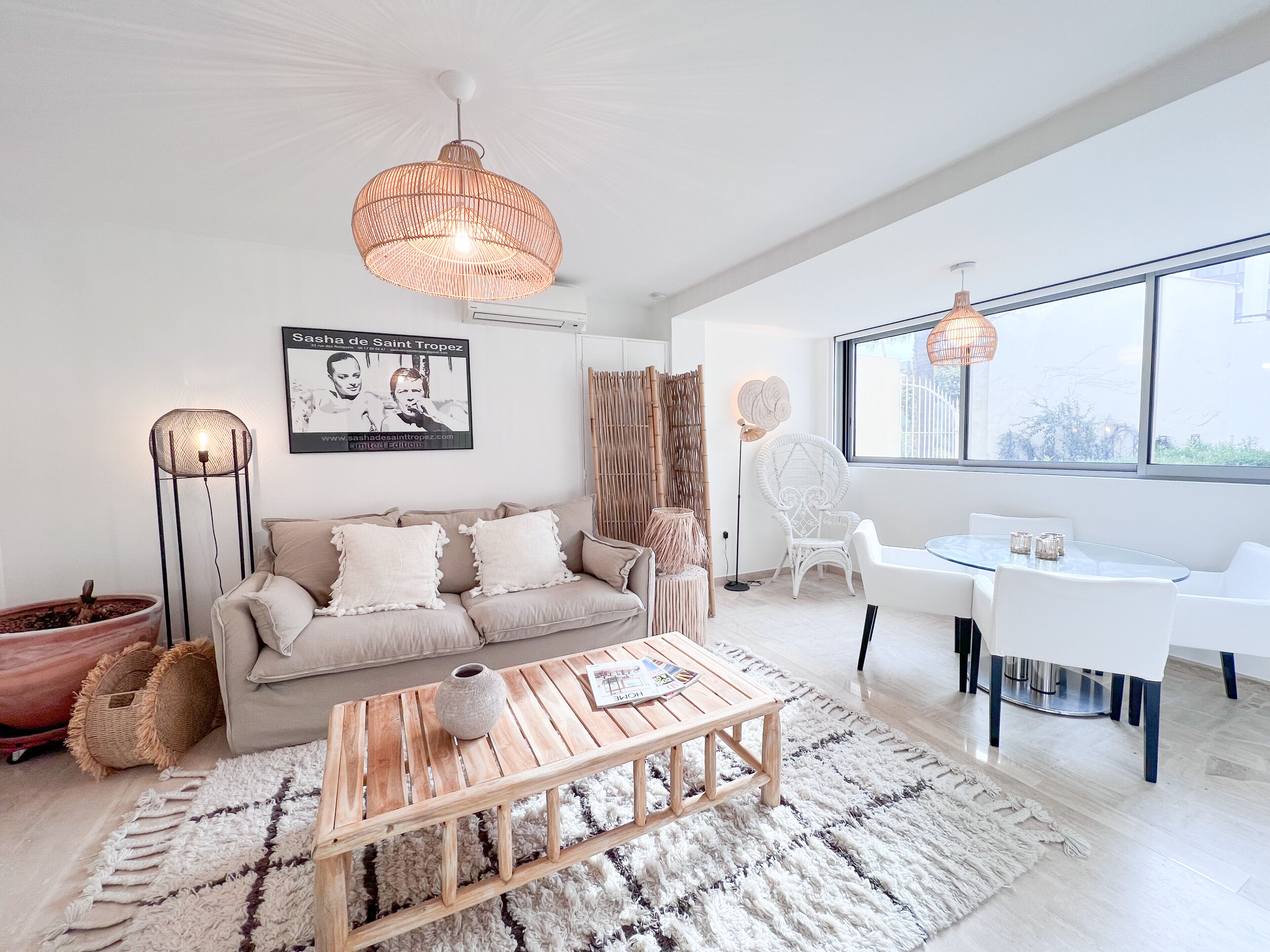 Ett modernt vardagsrum med en soffa, ett soffbord och en matplats med ett glasbord och stolar.