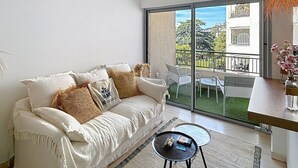 A modern living room with a sofa, a coffee table, and a view of a balcony with outdoor furniture. - Cannes: chic studio quiet in a secure residence 200m from the beaches (Cannes)