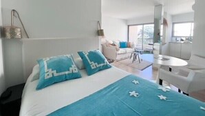 A modern hotel room with a large bed, a small seating area, and a view of the outdoors. - Cannes: chic studio quiet in a secure residence 200m from the beaches (Cannes)