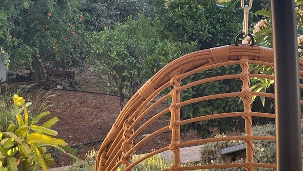 A wicker chair with a view of a garden and the sea. - Milo by the sea (Analipsi)
