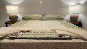 A neatly made bed with patterned bedding, two bedside lamps, and a woven basket on each nightstand. - Milo by the sea (Analipsi)
