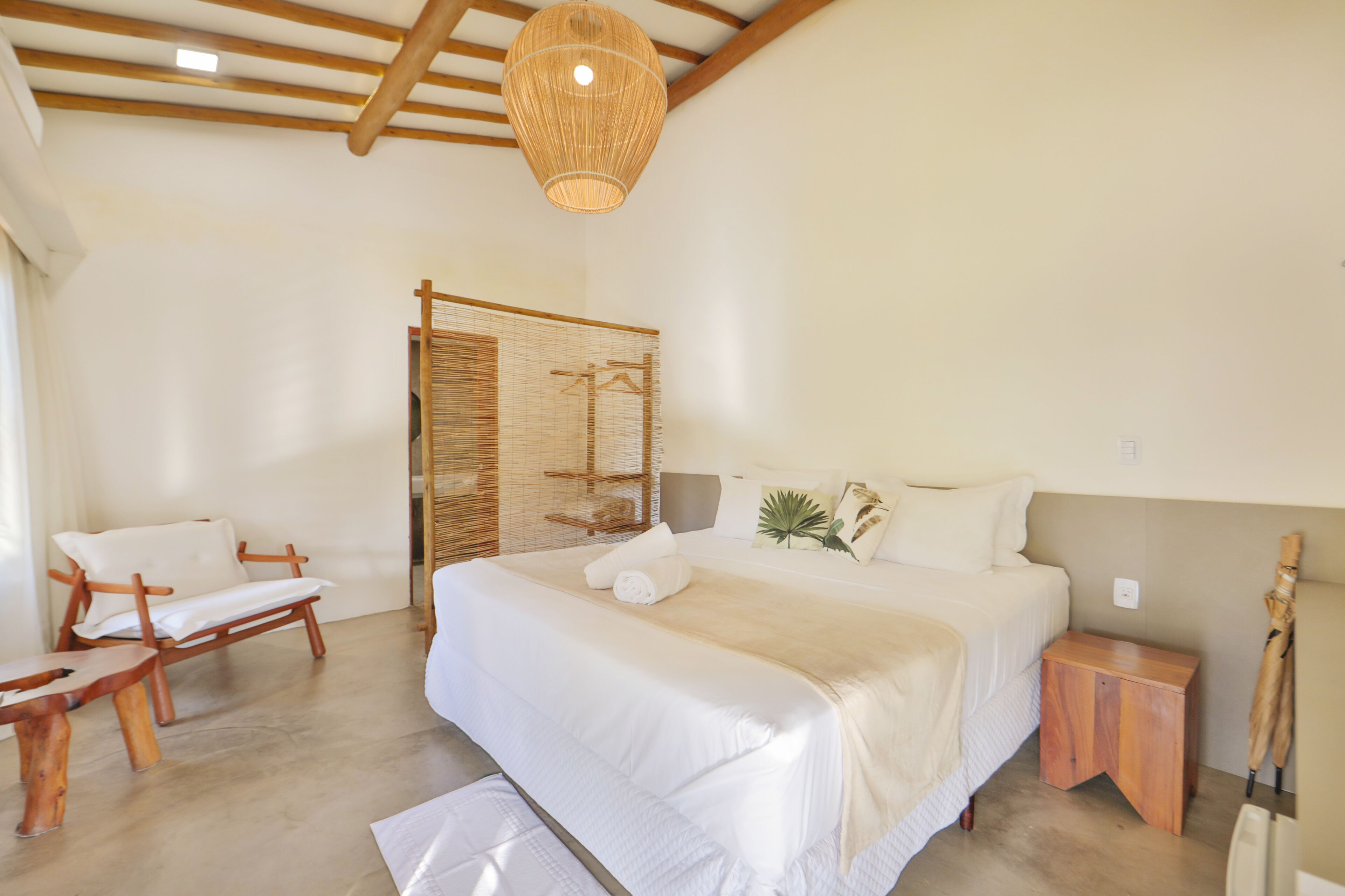 Un dormitorio con una cama grande, muebles de madera, una lámpara colgante y una mesita de noche de madera.