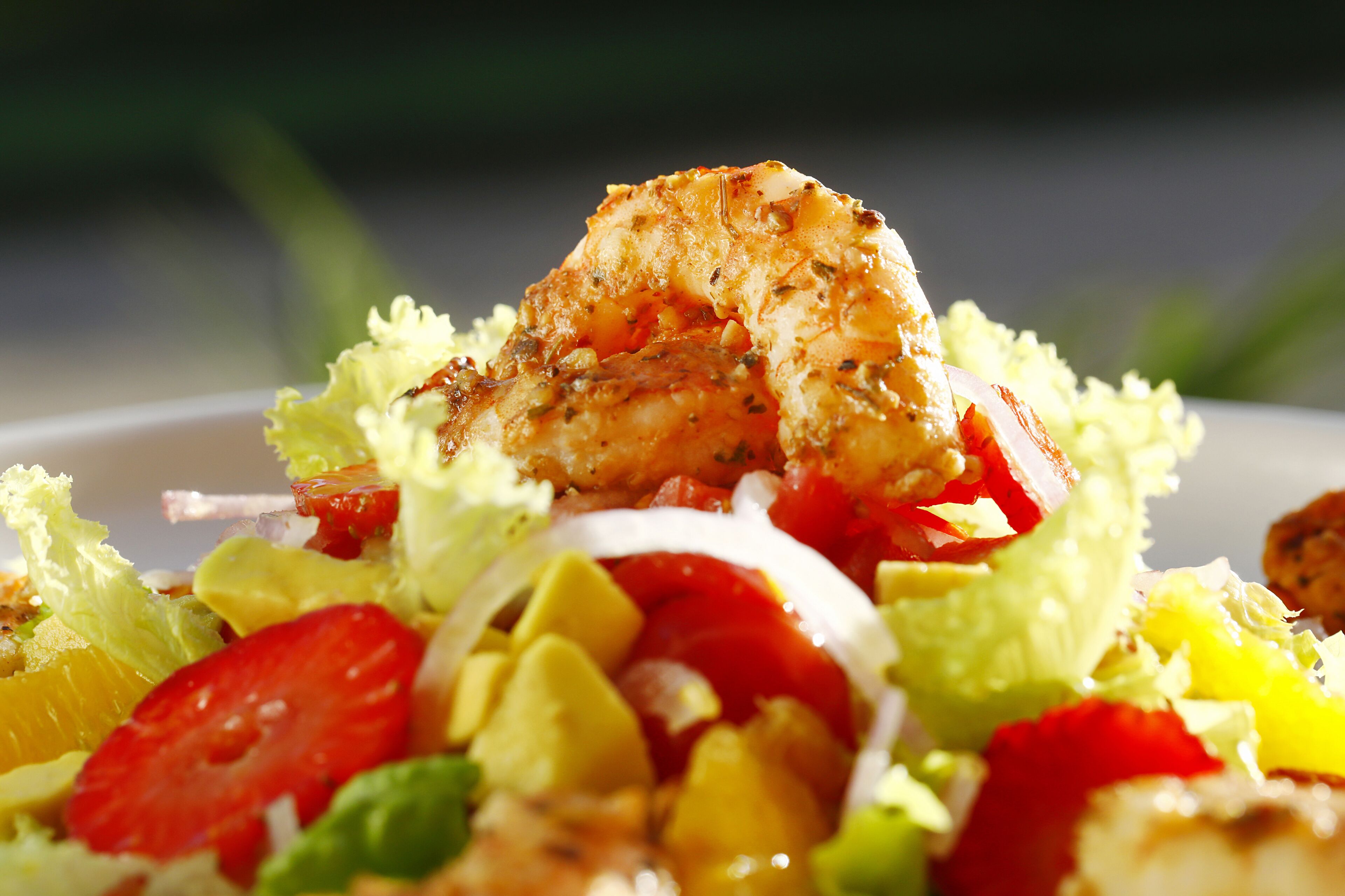 Une vue rapprochée d’une salade composée de poulet grillé, de tomates, d’oignons et d’avocat.