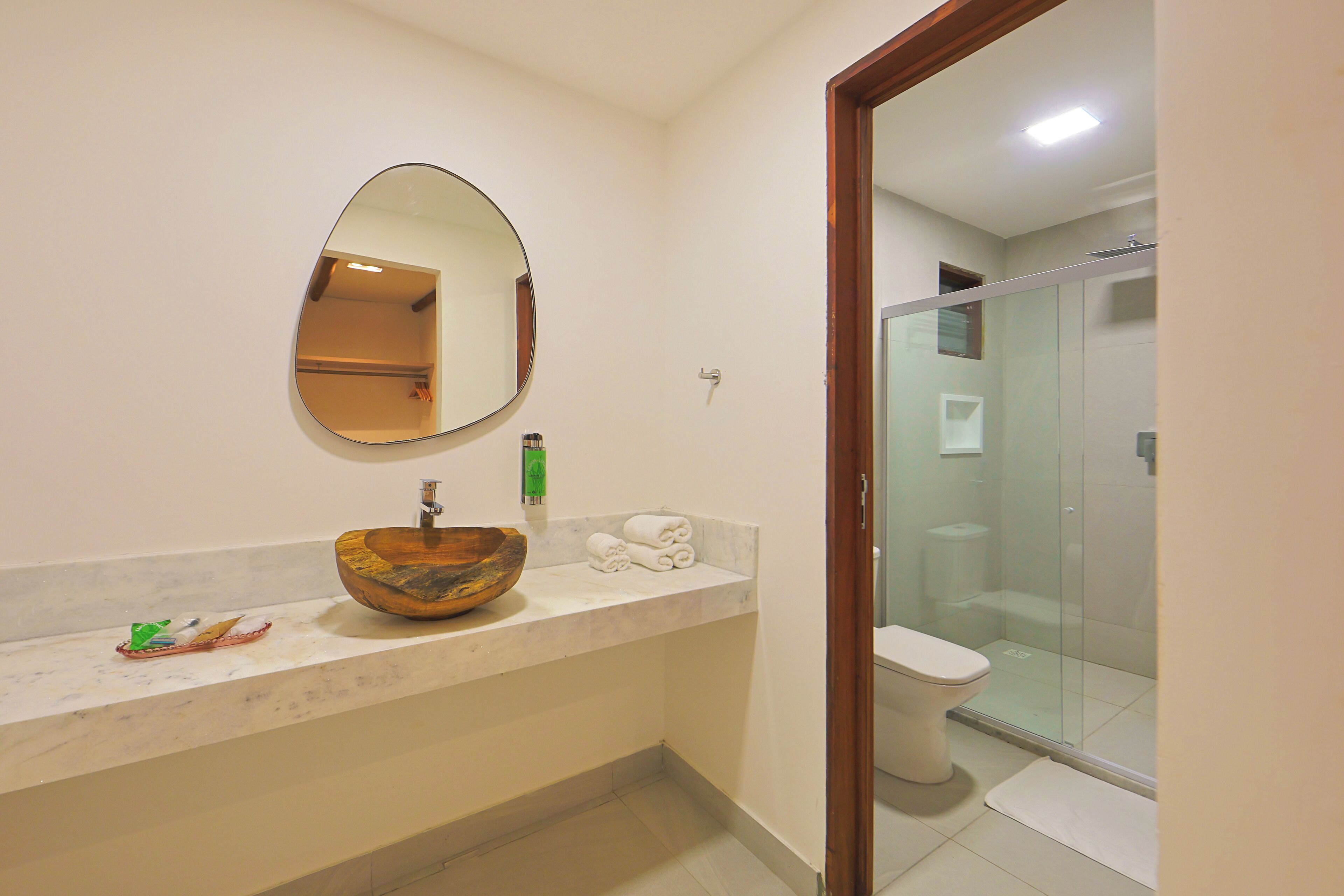 A bathroom with a wooden bowl sink, a mirror, and a toilet.