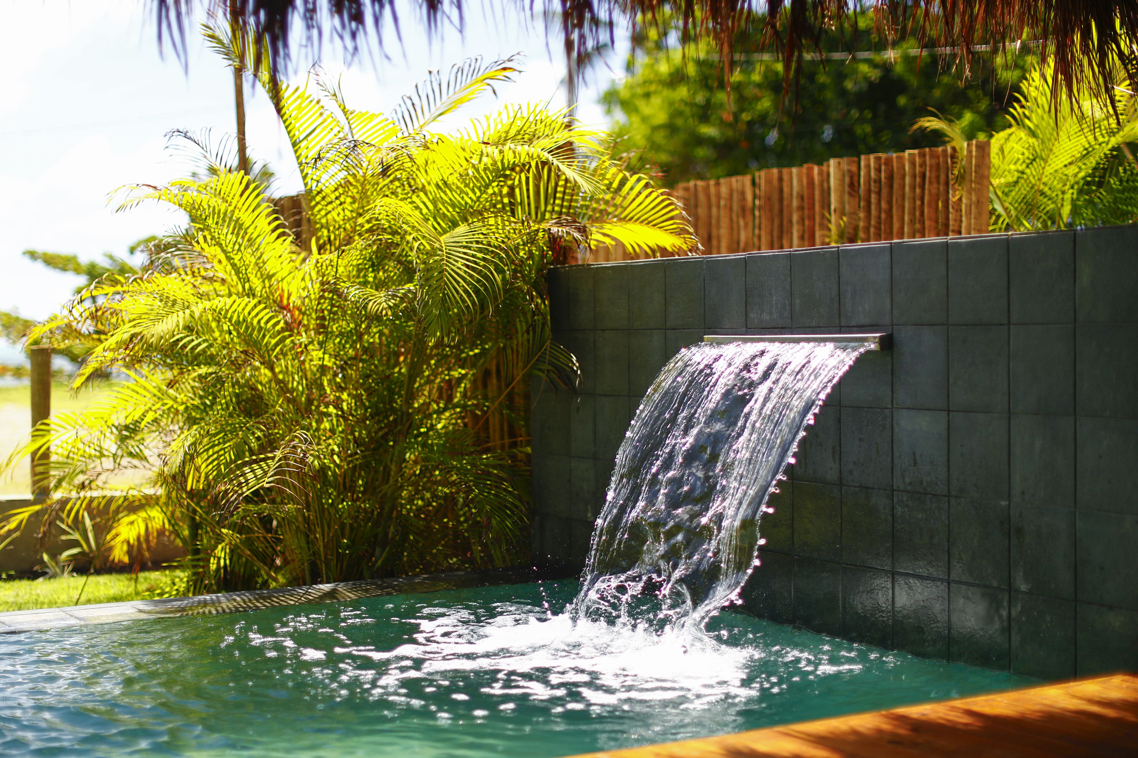 Ein Pool mit Wasserfall, umgeben von üppiger Vegetation.