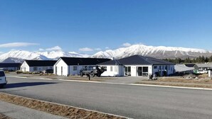 Un barrio residencial con casas, una calle pavimentada y montañas nevadas al fondo.
