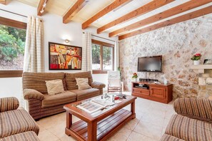 A living room with a sofa, armchairs, a coffee table, a TV, and a stone wall. - 3 Bedroom Villa, 300m to the Beach, Cala San Vicente (Cala San Vicente)
