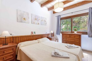 A bedroom with a wooden bed, a nightstand, a dresser, and a window with curtains. There are three framed pictures on the wall. - 3 Bedroom Villa, 300m to the Beach, Cala San Vicente (Cala San Vicente)