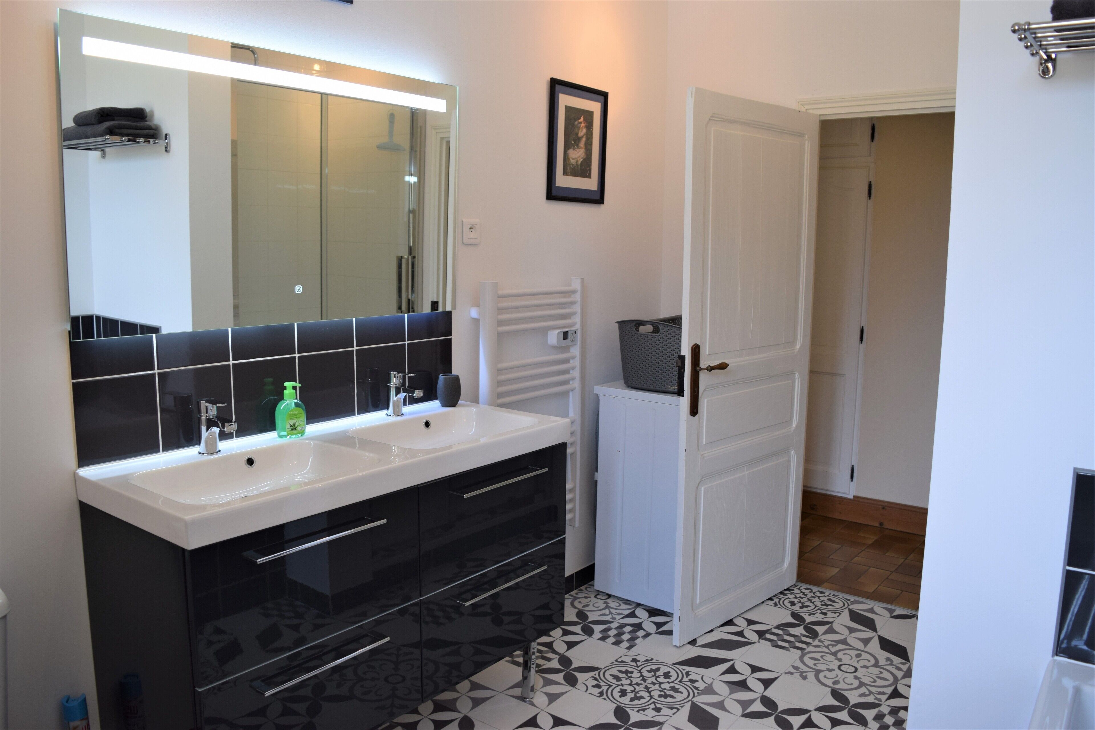 Een moderne badkamer met twee wastafels, een grote spiegel en een vloer met een patroon.