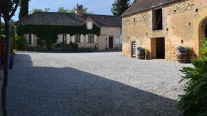 A courtyard with cobblestone ground, stone buildings, and a gravel path.