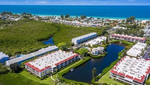 Oversigtsbillede af et resort med flere bygninger, et centralt vandelement og udsigt til havet.