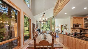 A spacious kitchen with wooden cabinets, a dining area with a large table, and large windows offering views of the outdoors.