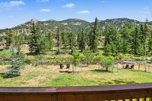 A mountainous landscape with a clear sky, a river, and a wooden deck with chairs. - Fall River Retreat - Monthly Long-term Vacation Rental 3 Bedroom Townhouse by RedAwning (Estes Park)