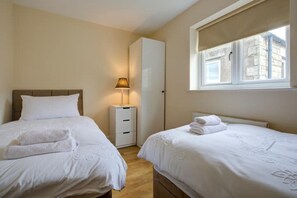A hotel room with two beds, a bedside table with a lamp, a wardrobe, and a window with a view of the outside. - Inglewood Apartment Yorkshire Dales National Park 3 Peaks & Lake District (Ingleton)