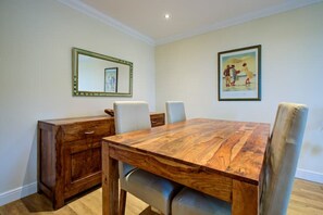 A dining room with a wooden table, two chairs, a wooden cabinet, and a framed picture on the wall. - Inglewood Apartment Yorkshire Dales National Park 3 Peaks & Lake District (Ingleton)