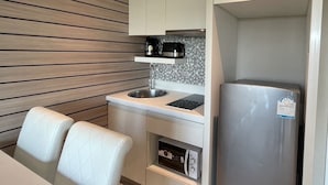 A compact kitchen with a built-in microwave, a stainless steel sink, and a refrigerator. - La Santir by PSR (Pattaya)