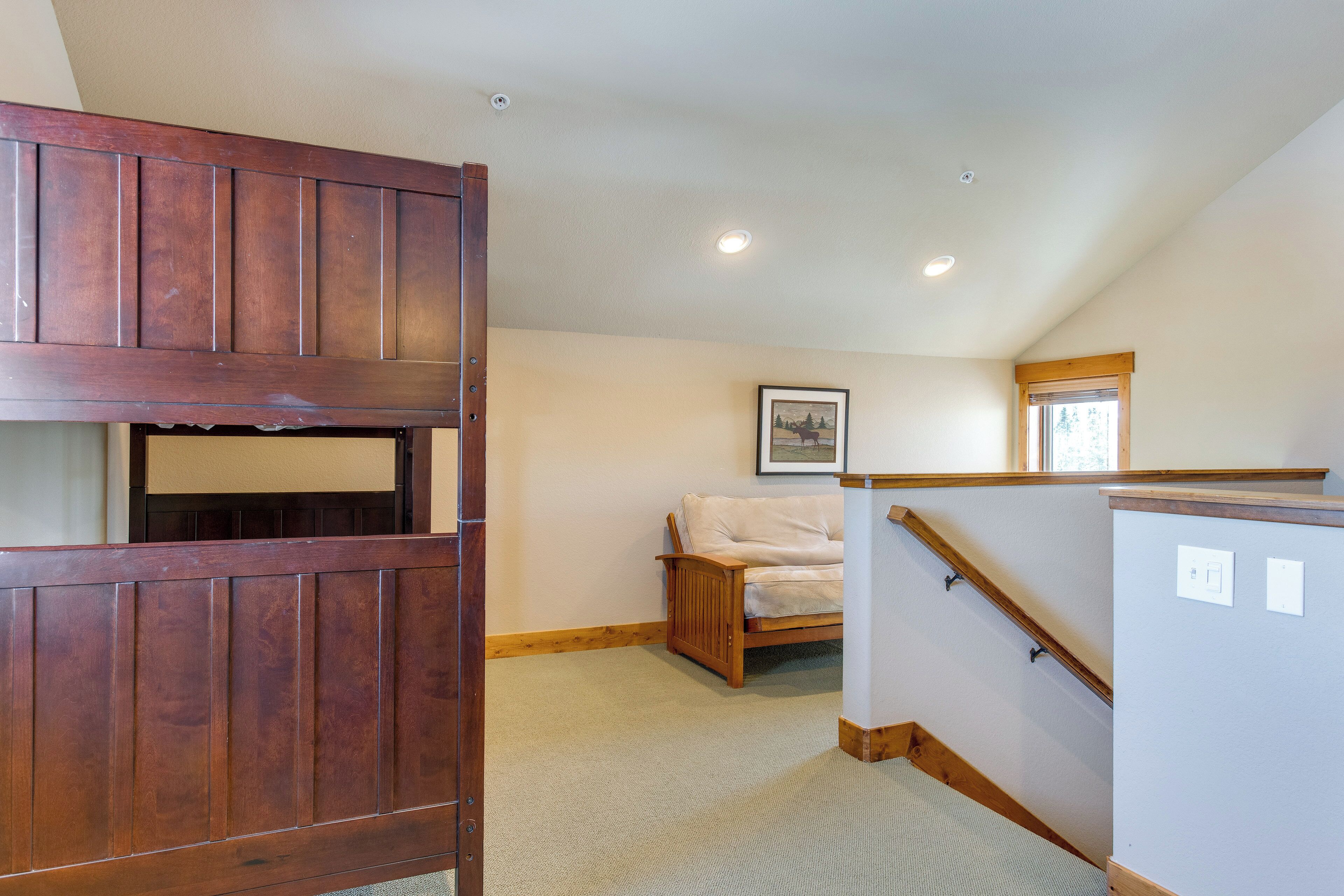 A room with a wooden bench, a sofa, a staircase, and a framed picture on the wall.