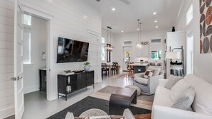 A modern living room with a flat-screen TV, a dining area, and a kitchen. - BVR 61 - The Good Life by Liquid Life (Orange Beach)