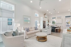 A modern living room with a sofa, ottoman, and a dining area with chairs and a table. - BVR 01 - Princess Sand Castle by Liquid Life (Orange Beach)