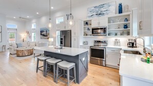 A modern kitchen with white cabinetry, stainless steel appliances, and a central island with bar stools.