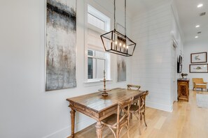 A dining area with a wooden table and chairs, a hanging light fixture, and artwork on the walls.