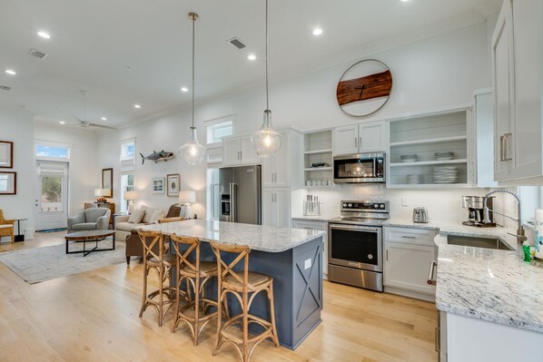 A modern kitchen with white cabinetry, stainless steel appliances, and a marble countertop.