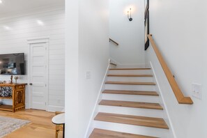 A staircase with wooden steps and a handrail, leading to a landing with a wall-mounted light fixture.