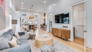 A modern living room with a grey sofa, a coffee table, and a TV mounted on the wall.