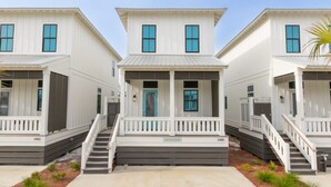 A row of three-story white buildings with a central porch and a staircase leading to the entrance.