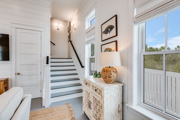 A staircase with white railings, a white door, and a wall-mounted lamp.