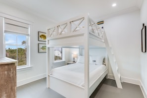 A bunk bed room with a view of trees through the window.