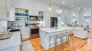 Una cocina moderna con armarios blancos, electrodomésticos de acero inoxidable y una isla central con taburetes de bar.