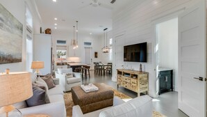 Ein geräumiges Wohnzimmer mit einer Couch, Hocker und einem Essbereich mit Stühlen und einem Tisch.