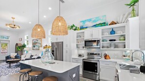 Una cocina moderna con armarios blancos, electrodomésticos de acero inoxidable y una isla central con taburetes.