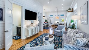 A spacious living room with a large TV, a dining area, and a kitchen.