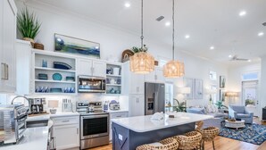 A modern kitchen with white cabinetry, stainless steel appliances, and a central island with bar stools.
