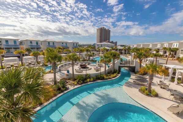 A resort with a large swimming pool, palm trees, and multiple buildings.