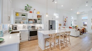 Una cocina amplia con armarios blancos, electrodomésticos de acero inoxidable y una isla central con taburetes de bar.