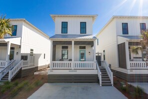 A row of white, two-story houses with a central porch and steps leading to the entrance.