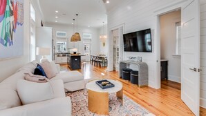 A spacious living area with a sofa, coffee table, and a TV mounted on the wall.