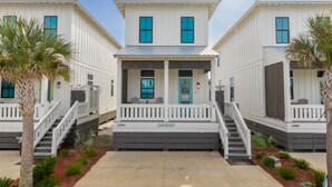 A row of white buildings with blue windows and a central porch.