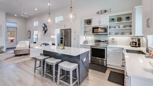 A modern kitchen with white cabinetry, stainless steel appliances, and a central island with bar stools.
