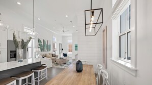 A modern kitchen with white cabinetry, a wooden dining table, and pendant lighting. - BVR 67 - Kit Kamp by Liquid Life (Orange Beach)