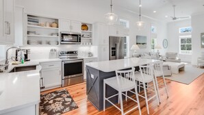 A modern kitchen with white cabinetry, stainless steel appliances, and a central island with bar stools.