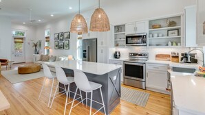 Una cocina moderna con armarios blancos, electrodomésticos de acero inoxidable y una isla central con taburetes de bar.