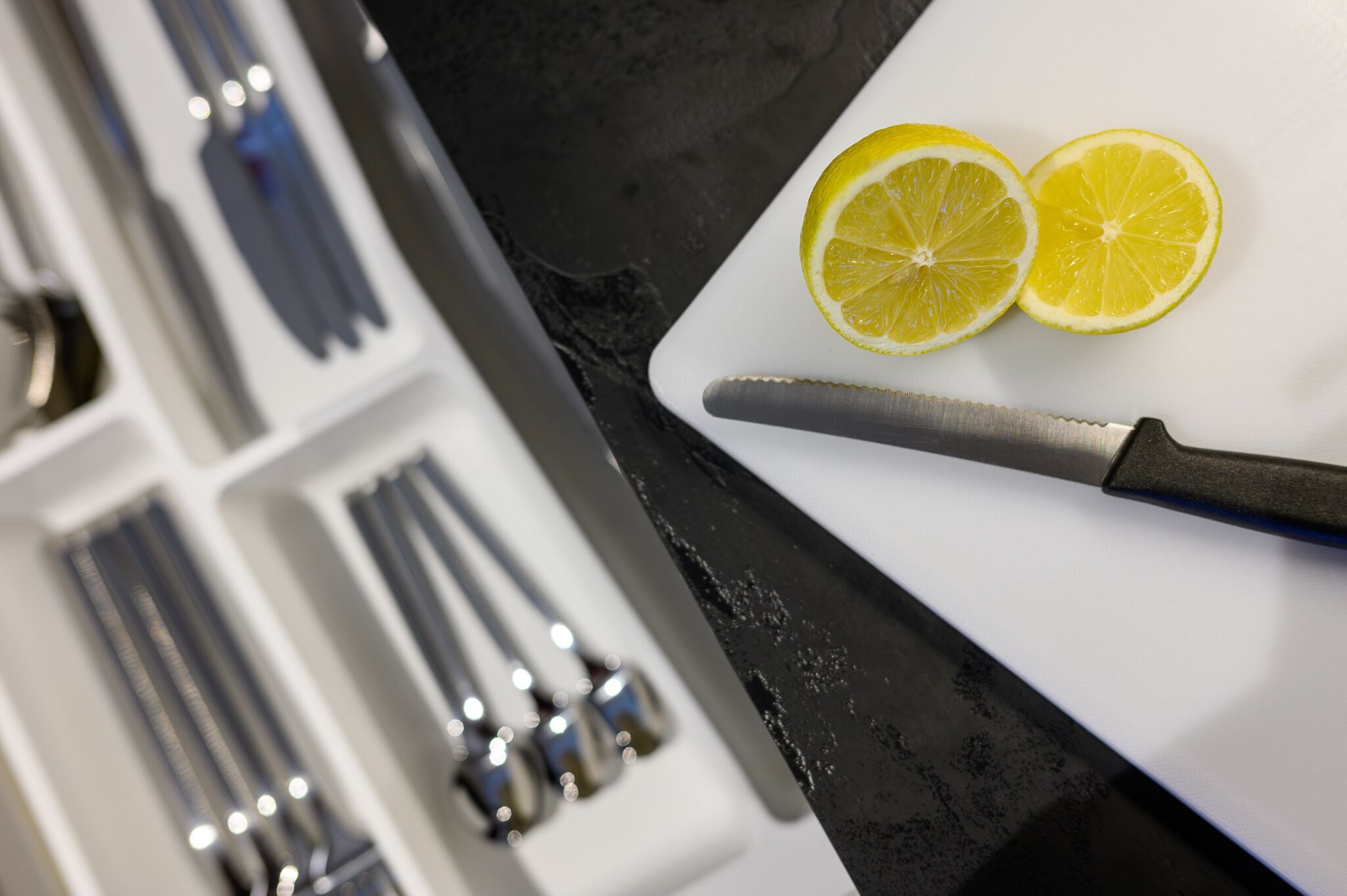 Una encimera de cocina con una tabla de cortar, dos limones cortados por la mitad y un cuchillo.