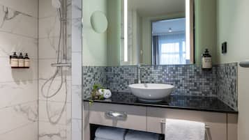 A modern bathroom with a large mirror, a white sink, and a shower area.
